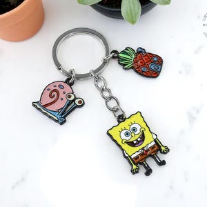 Schattige Slak Sleutelhanger – Emaille Metalen Tashanger voor Kinderen, Anime Sleutelring, Rugzak Accessoire & Cadeau Idee