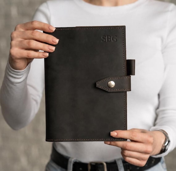 Full-grain leather A5 journal cover with pen holder and refillable pages — a genuinely craftsman-made desk object that gets better with age.
