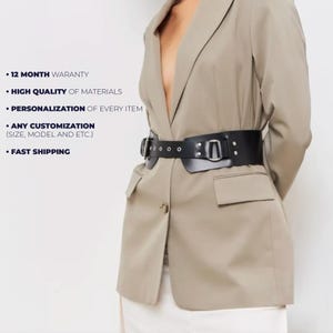 May include: A black leather belt with a wide design, featuring a large buckle and multiple eyelets. The belt is worn over a tan blazer. The image also includes text: "12 MONTH WARANTY", "HIGH QUALITY OF MATERIALS", "PERSONALIZATION OF EVERY ITEM", "ANY CUSTOMIZATION", and "FAST SHIPPING".