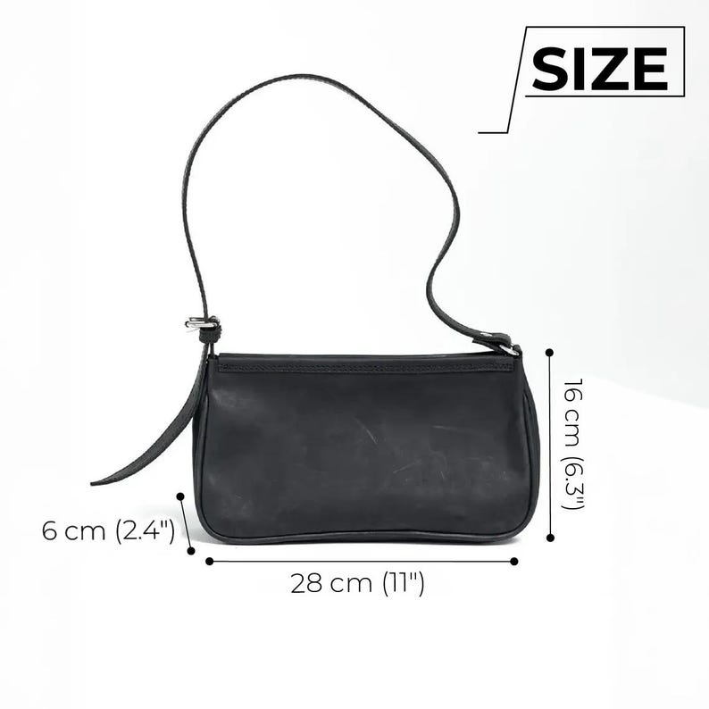 K&ouml;nnte beinhalten: Schwarze Leder-Umh&auml;ngetasche mit langem Riemen. Die Tasche ist 28 cm lang, 16 cm hoch und 6 cm breit. Die Tasche hat eine einfache, rechteckige Form und einen Klappenverschluss.
