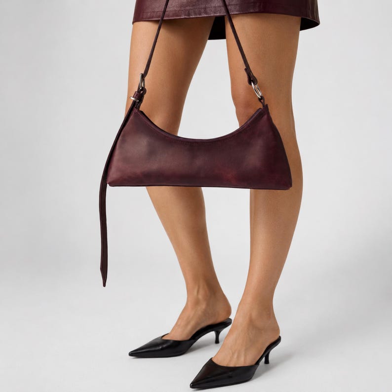 Small leather shoulder bag for women in genuine leather with a slim strap, zipper closure, and minimalist baguette bag shape.