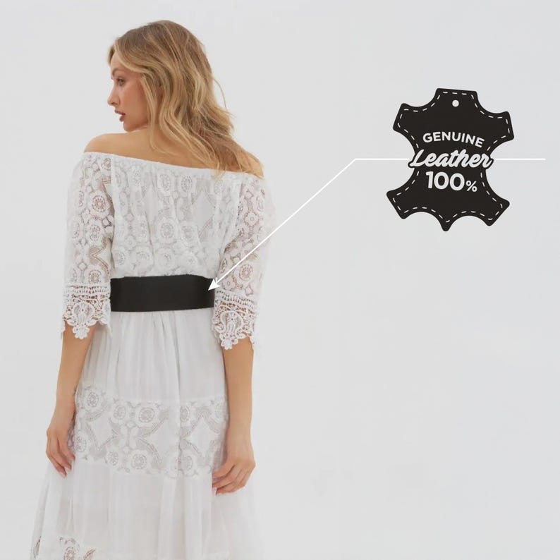 May include: A white off-the-shoulder dress with lace detailing and a black leather belt. The dress has a tiered skirt and three-quarter sleeves. The image includes a tag that reads "GENUINE Leather 100%."