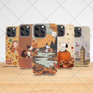 Könnte beinhalten: Fünf Handyhüllen mit Herbstmotiven. Die Hüllen zeigen Illustrationen eines Mädchens, einer Katze, Snoopy und Big Ben. Die Farbpalette umfasst Orange, Braun und Beige, mit Herbstblättern und Kürbissen.