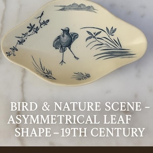 May include: Cream-coloured, asymmetrical leaf-shaped dish with a bird and nature scene in blue. The design includes a bird, foliage, and a landscape. The text on the image reads "BIRD & NATURE SCENE - ASYMMETRICAL LEAF SHAPE - 19TH CENTURY."