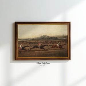 K&ouml;nnte beinhalten: Ein gerahmter Vintage-Druck, der ein Pferderennen mit drei Pferden und Jockeys zeigt. Das Kunstwerk hat einen braunen Holzrahmen und den Text "Bloom Ridge Prints DIGITAL ART" unten.