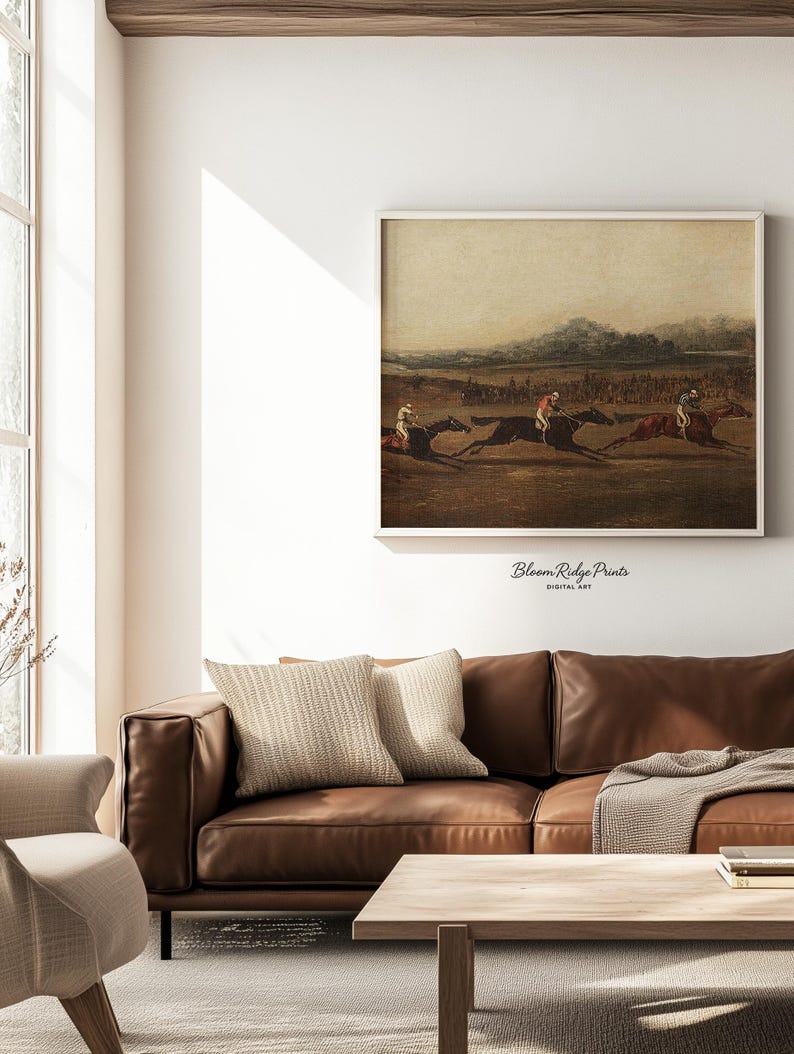 K&ouml;nnte beinhalten: Ein gerahmter Vintage-Druck, der ein Pferderennen mit drei Jockeys zeigt. Das Kunstwerk in ged&auml;mpften T&ouml;nen h&auml;ngt &uuml;ber einem braunen Ledersofa. Der Text "Bloom Ridge Prints DIGITAL ART" ist sichtbar. Die Szene erweckt einen historischen Eindruck.