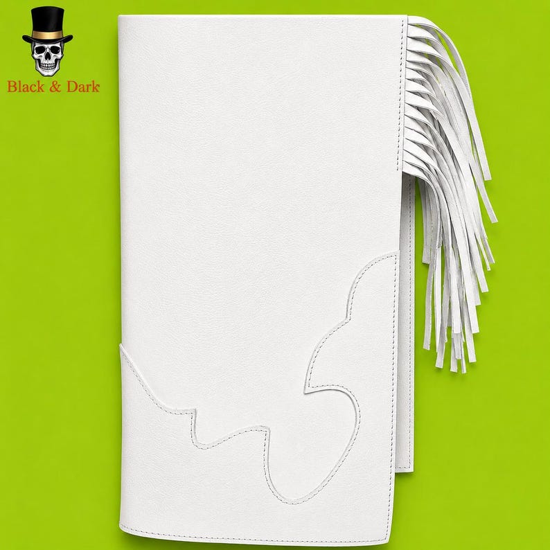 May include: A white rectangular leather-like accessory featuring a long fringe detail on the right side and decorative stitching along the bottom edge. The top left corner displays a small black top hat and skull logo with the text Black & Dark.