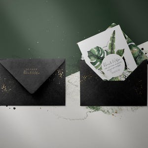 May include: Black envelope with gold glitter and a white card with green watercolor leaves and the text "Roni & Wilam Our Wedding Ceremony and your presence is greatly appreciated".