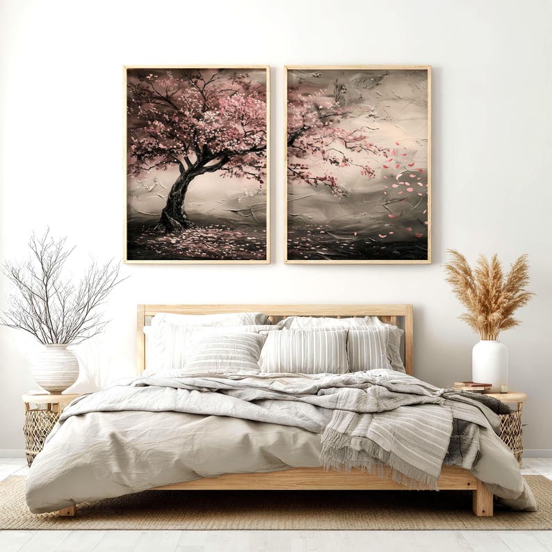 a serene bedroom scene with a large bed, a nightstand, and two framed paintings of trees with pink blossoms hanging on the wall above the bed.