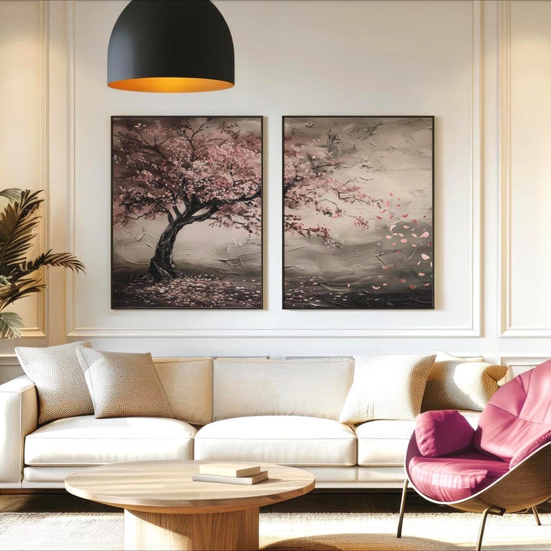 a cozy living room with a white sofa, a round wooden coffee table, and two framed paintings of cherry blossom trees hanging on the wall.