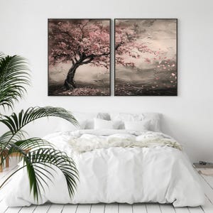 a bedroom with a large bed and two framed paintings of a tree with pink flowers hanging above it.