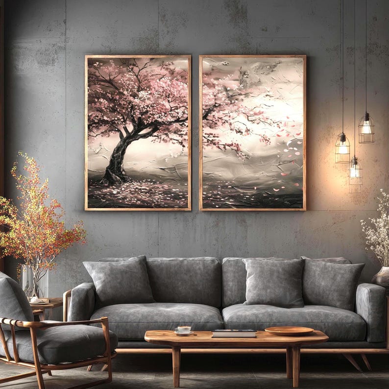 a living room with a gray sofa, a wooden coffee table, and two framed paintings of a tree with pink flowers hanging on the wall above the sofa.