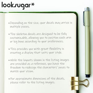 May include: An open notebook with green edging, text about skeleton decals, and a pen. The text details the decals' customisability and flexible display options. A gold binder clip secures the notebook. The brand name "looksugar*" is at the top.