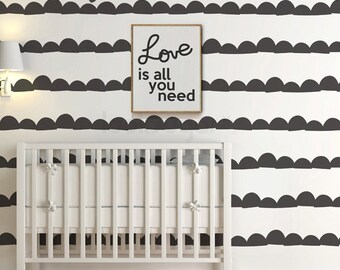 May include: A white crib with a black and white patterned wall behind it. The wall pattern is a series of black half-circles. A framed print with the text "Love is all you need" is hanging on the wall.