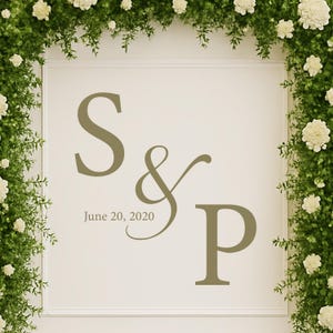 Puede incluir: Un letrero color crema con las iniciales "S & P" y la fecha "20 de junio de 2020" en un suave tono verde. El letrero est&aacute; enmarcado por una exuberante disposici&oacute;n de vegetaci&oacute;n y flores blancas, creando una est&eacute;tica natural y elegante.