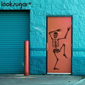 May include: An orange door with a black skeleton graphic against a turquoise brick wall. A turquoise roller shutter door is to the left. The text "looksugar*" is in the upper left corner. A red pole is in front of the roller shutter door.
