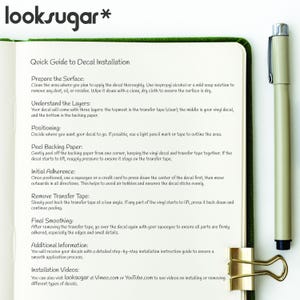 Puede incluir: Cuaderno abierto con borde verde, con una gu&iacute;a de instalaci&oacute;n de calcoman&iacute;as. La gu&iacute;a incluye pasos como la preparaci&oacute;n de la superficie y la eliminaci&oacute;n de la cinta de transferencia. Un clip dorado y un bol&iacute;grafo tambi&eacute;n son visibles.