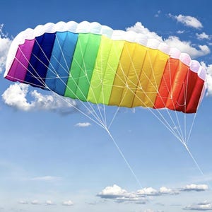 Può includere: Un colorato aquilone arcobaleno contro un cielo blu con soffici nuvole bianche. L'aquilone presenta una serie di pannelli vibranti nei colori dell'arcobaleno, dal viola al rosso, con accenti bianchi. Fili bianchi si estendono dall'aquilone.