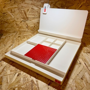 Puede incluir: Un organizador blanco con m&uacute;ltiples compartimentos y una placa base Lego roja. Cuenta con una luz LED y un panel trasero con bisagras. Dise&ntilde;ado para almacenar y organizar objetos peque&ntilde;os, ideal para pasatiempos.