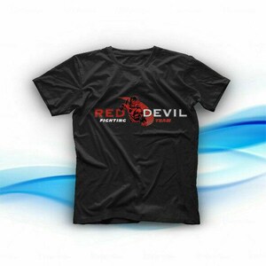 Puede incluir: Camiseta negra con las palabras "RED DEVIL FIGHTING TEAM" en rojo y blanco. El diseño incluye un gráfico de diablo rojo. La camiseta es de cuello redondo.