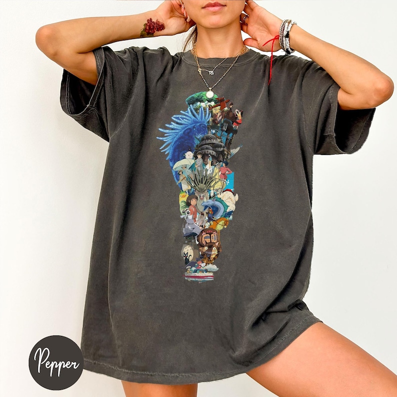 May include: Dark gray t-shirt featuring a colorful collage of anime characters. The graphic includes various figures in shades of blue, red, and yellow. The shirt has short sleeves and a relaxed fit. The word "Pepper" is printed on the bottom left.
