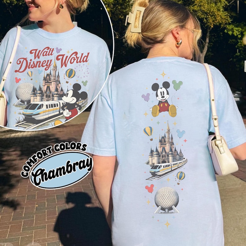 Pu&ograve; includere: Una t-shirt azzurro chiaro con una stampa grafica di Topolino, il castello di Walt Disney World, una monorotaia e la sfera di Epcot. Il design include mongolfiere colorate e piccoli accenti a stella, con il testo Walt Disney World.