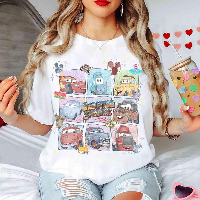 Puede incluir: Camiseta blanca con una colorida cuadr&iacute;cula de personajes de la pel&iacute;cula Cars. El dise&ntilde;o incluye a Rayo McQueen, Mate y otros personajes de Radiator Springs. La camiseta tiene cuello redondo y mangas cortas, perfecta para uso casual.