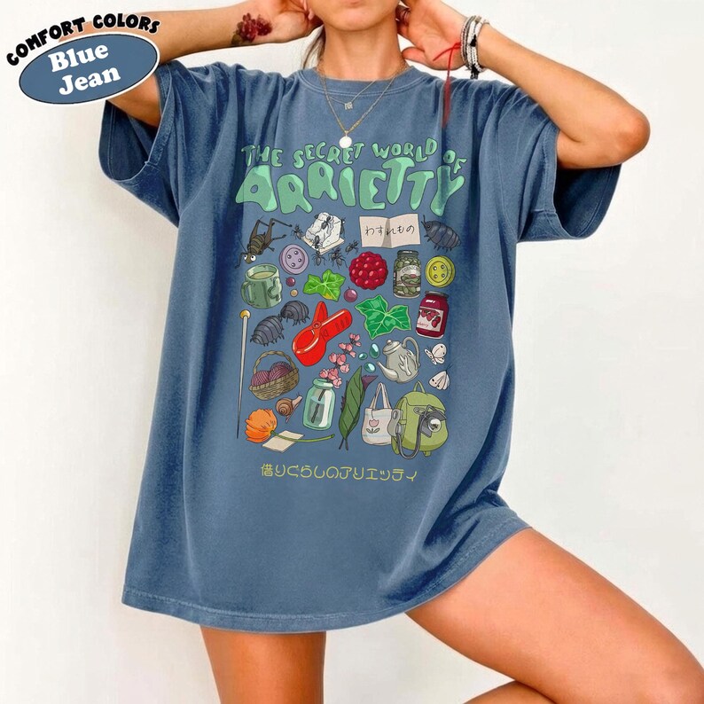 May include: Blue jean comfort colors t-shirt with a graphic from "The Secret World of Arrietty". The design features various illustrations including insects, food, and tools. The text is in English and Japanese.