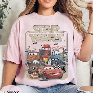 Puede incluir: Camiseta rosa claro con un dise&ntilde;o de personajes de la pel&iacute;cula Cars, con el logo de Star Wars encima. El dise&ntilde;o incluye a Rayo McQueen y otros veh&iacute;culos animados. La camiseta tiene un corte holgado y oversize.