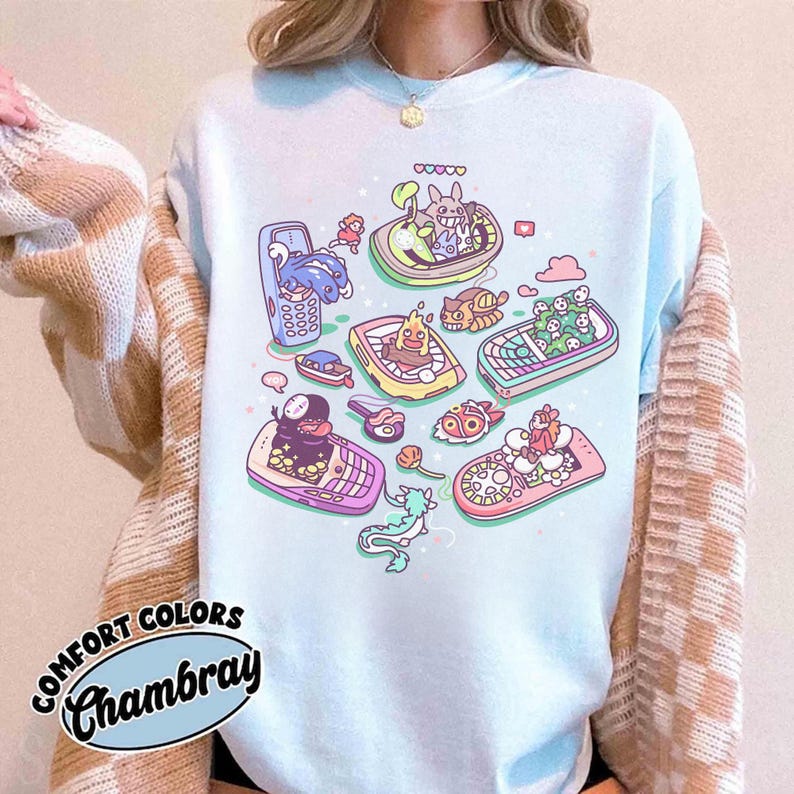 K&ouml;nnte beinhalten: Hellblaues Comfort Colors Chambray T-Shirt mit einem skurrilen Design von Zeichentrickfiguren in Booten in Form von Retro-Handys. Das Design umfasst verschiedene Farben und Details.