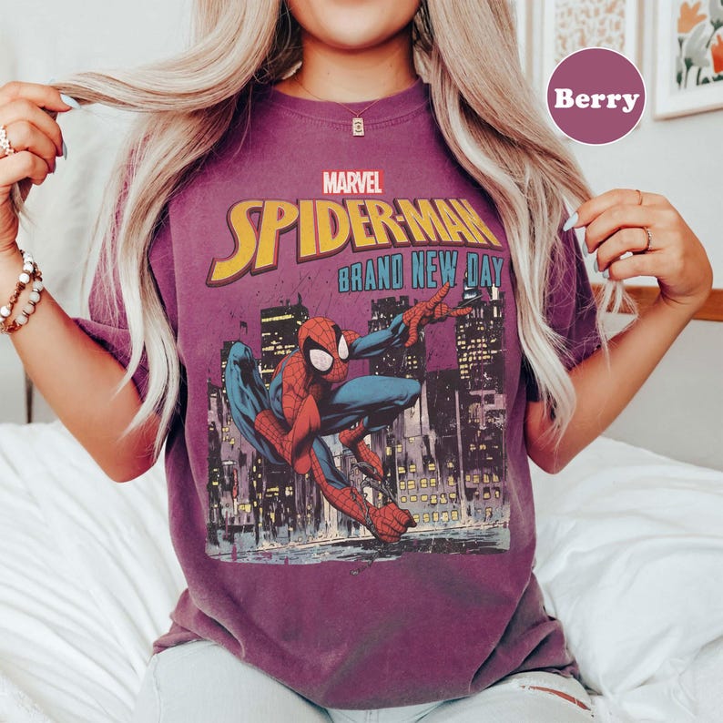 Puede incluir: Camiseta color bayas con un gr&aacute;fico de Spider-Man de Marvel. El dise&ntilde;o incluye las palabras "Spider-Man Brand New Day" y una ilustraci&oacute;n de Spider-Man frente a un horizonte urbano. La camiseta tiene mangas cortas.