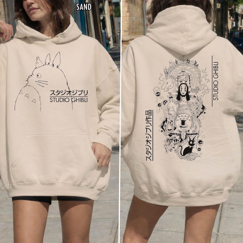 Może przedstawiać: Beżowa bluza z kapturem z czarną grafiką postaci i tekstem ze studia Ghibli. Prz&oacute;d przedstawia ilustrację postaci i japoński tekst. Tył przedstawia szczeg&oacute;łową ilustrację z japońskim tekstem i napisem "STUDIO GHIBLI" w języku angielskim.