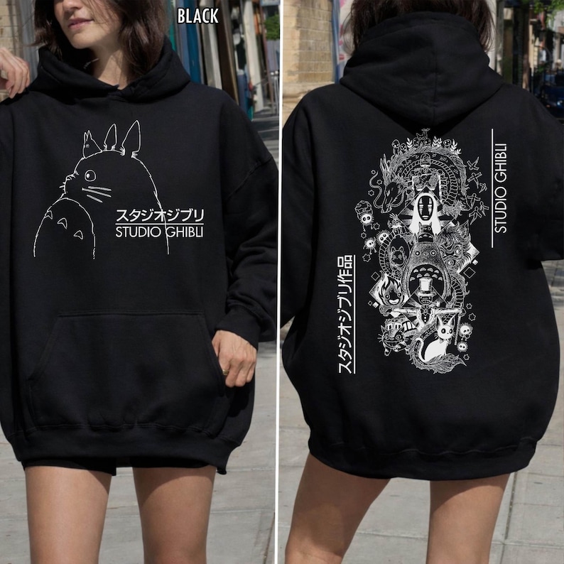 Może przedstawiać: Czarna bluza z kapturem Studio Ghibli z białym konturem Totoro z przodu i szczeg&oacute;łową grafiką z tyłu. Bluza zawiera napis "STUDIO GHIBLI" oraz japoński tekst.