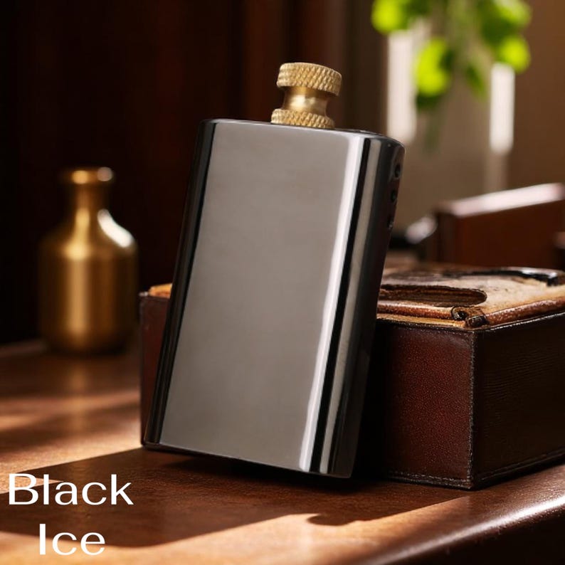 Puede incluir: Una petaca negra rectangular con una tapa dorada. La petaca tiene una superficie brillante y reflectante. Las palabras "Black Ice" est&aacute;n impresas en blanco en la parte inferior de la imagen. La petaca est&aacute; sobre una superficie de madera.