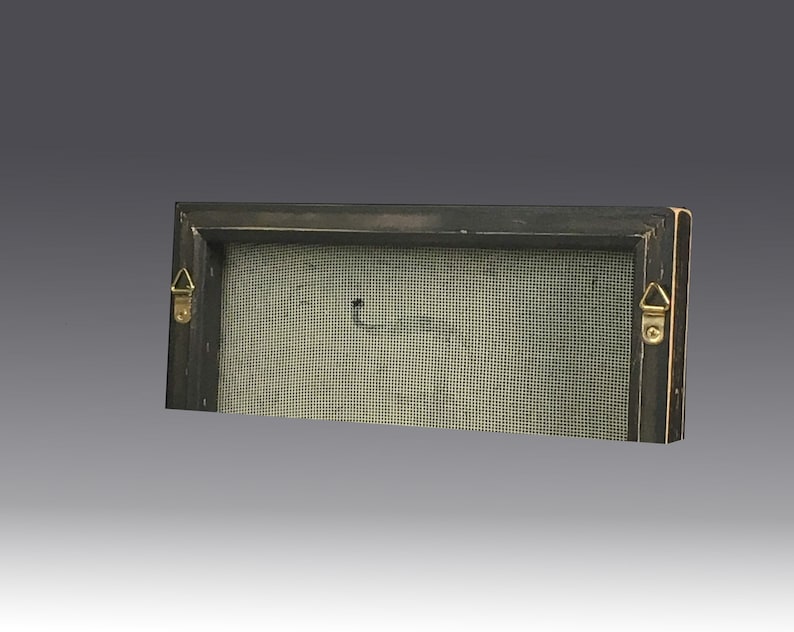 May include: A rectangular wooden frame with a dark finish, featuring a light-colored mesh screen stretched across the center. Two gold-toned triangular metal hanging brackets are attached to the left and right sides of the frame's back edge.