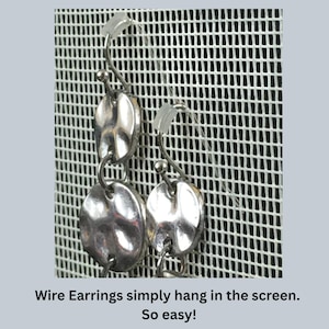 May include: Two silver-toned drop earrings featuring hammered circular metal discs connected by jump rings. The earrings have curved wire hooks with small clear plastic backings. The text below reads: Wire Earrings simply hang in the screen. So easy!