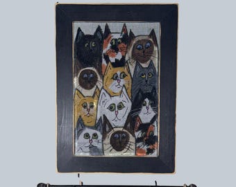 May include: A framed artwork featuring a grid of cat portraits in various colors and patterns. The cats have different eye colors and markings, set against a mesh background. The frame is black, and a decorative rod is below.