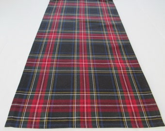 May include: A red, white, blue, and green plaid table runner. The runner has a woven texture and is made of fabric.