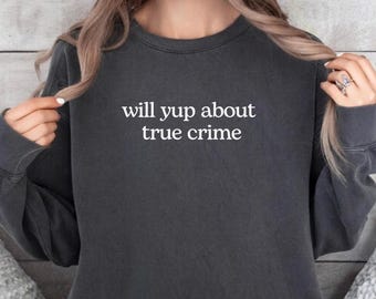 Op de afbeelding: Een donkergrijs sweatshirt met de witte tekst "will yup about true crime". De sweatshirt heeft een ronde hals en lijkt gemaakt van een zacht materiaal. Het woord "Pepper" staat onderaan de afbeelding.