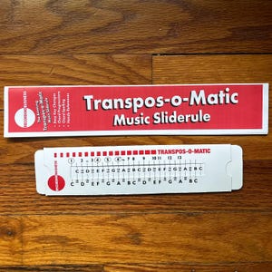 May include: Two Transpos-o-Matic Music Sliderule tools. The top one is red and white with the text "Transpos-o-Matic Music Sliderule". The bottom one is white with musical notes and numbers. The tools are for easy key changes and chord progressions.