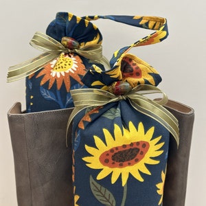 May include: Two fabric bags with sunflower patterns and brown ribbon ties. The bags are filled with cedar chips and are designed to absorb moisture and odors in shoes.
