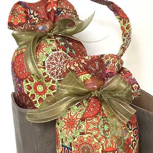 May include: Two fabric pouches with a colorful mandala pattern and gold ribbon bows. The pouches are in a brown leather bag.