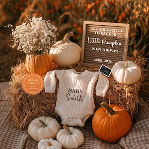 May include: A baby announcement scene with a cream-coloured onesie, pumpkins, and a letter board. The onesie has "BABY Smith" printed on it. The letter board says "WE ARE EXCITED TO SAY OUR Little Pumpkin IS ON THE WAY! APRIL 2026". The scene is set with autumnal colours.