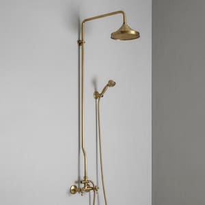 Puede incluir: Un conjunto de ducha dorado con un cabezal de ducha redondo y una ducha de mano. El conjunto está montado en una pared gris claro. El cabezal de ducha tiene unos 20 cm de diámetro.