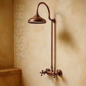 May include: A copper-toned shower fixture featuring a curved shower head and a vertical pipe. It has cross-shaped handles for water control. The word "BRASSRY" is visible in the background.
