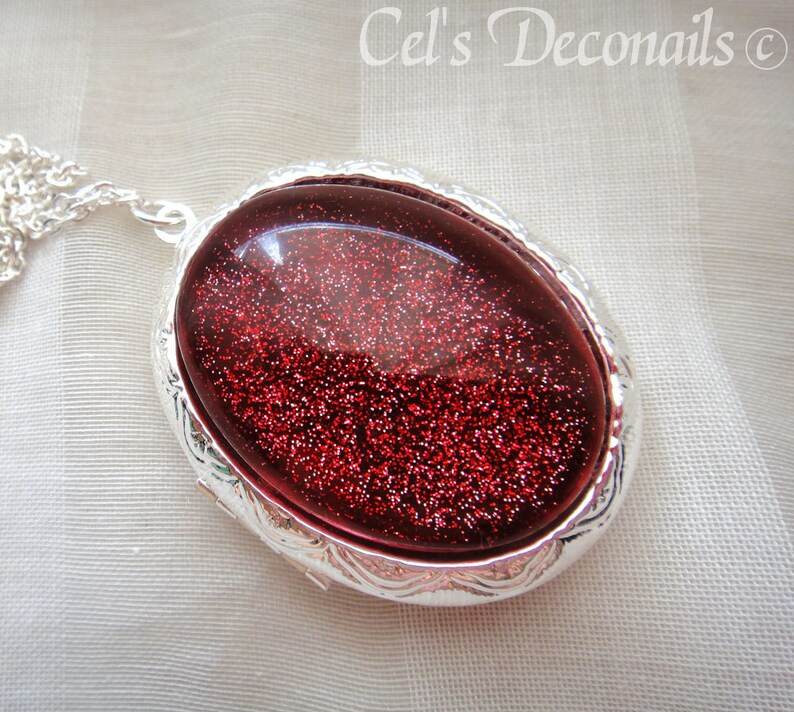 May include: A silver locket necklace with a red glitter filled oval pendant.