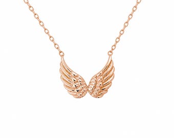 May include: Rose gold necklace featuring a pair of detailed wing pendants. The wings are symmetrical, with textured feather detailing. The chain is delicate and also rose gold. The necklace is displayed against a white background.
