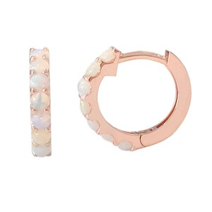 May include: A pair of rose gold hoop earrings with a row of white opal stones around the hoop.