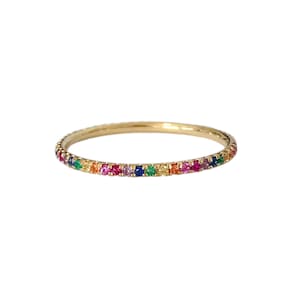 May include: A gold band ring with a rainbow of tiny gemstones set around the entire band.