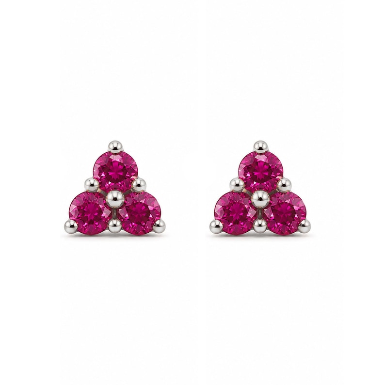 May include: A pair of stud earrings featuring three round-cut, vibrant pink stones arranged in a triangular cluster. Each stone is held in place by a polished silver-toned metal setting, creating a symmetrical and cohesive design for each earring.